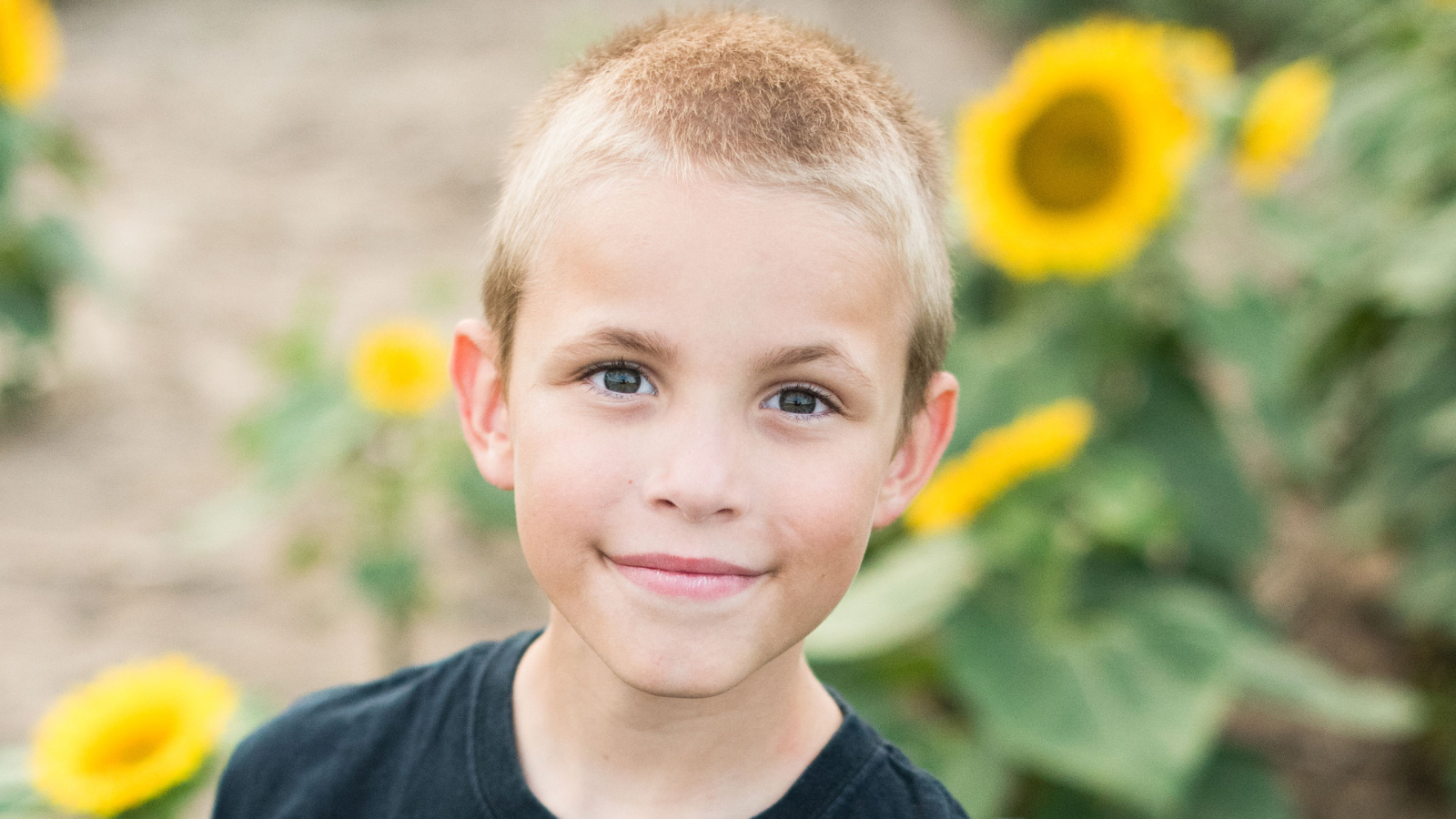 Gillian's son, Matthew, smiling in a field of sunflowers